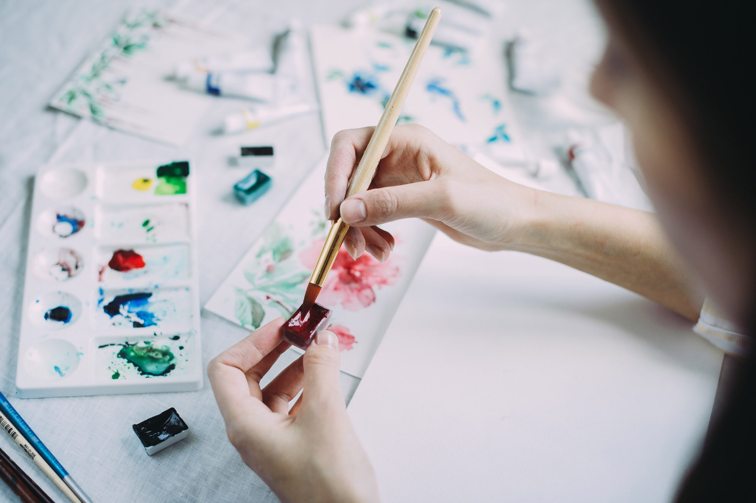 Beautiful girl artist paints with watercolors in a bright studio. Art. Drawing